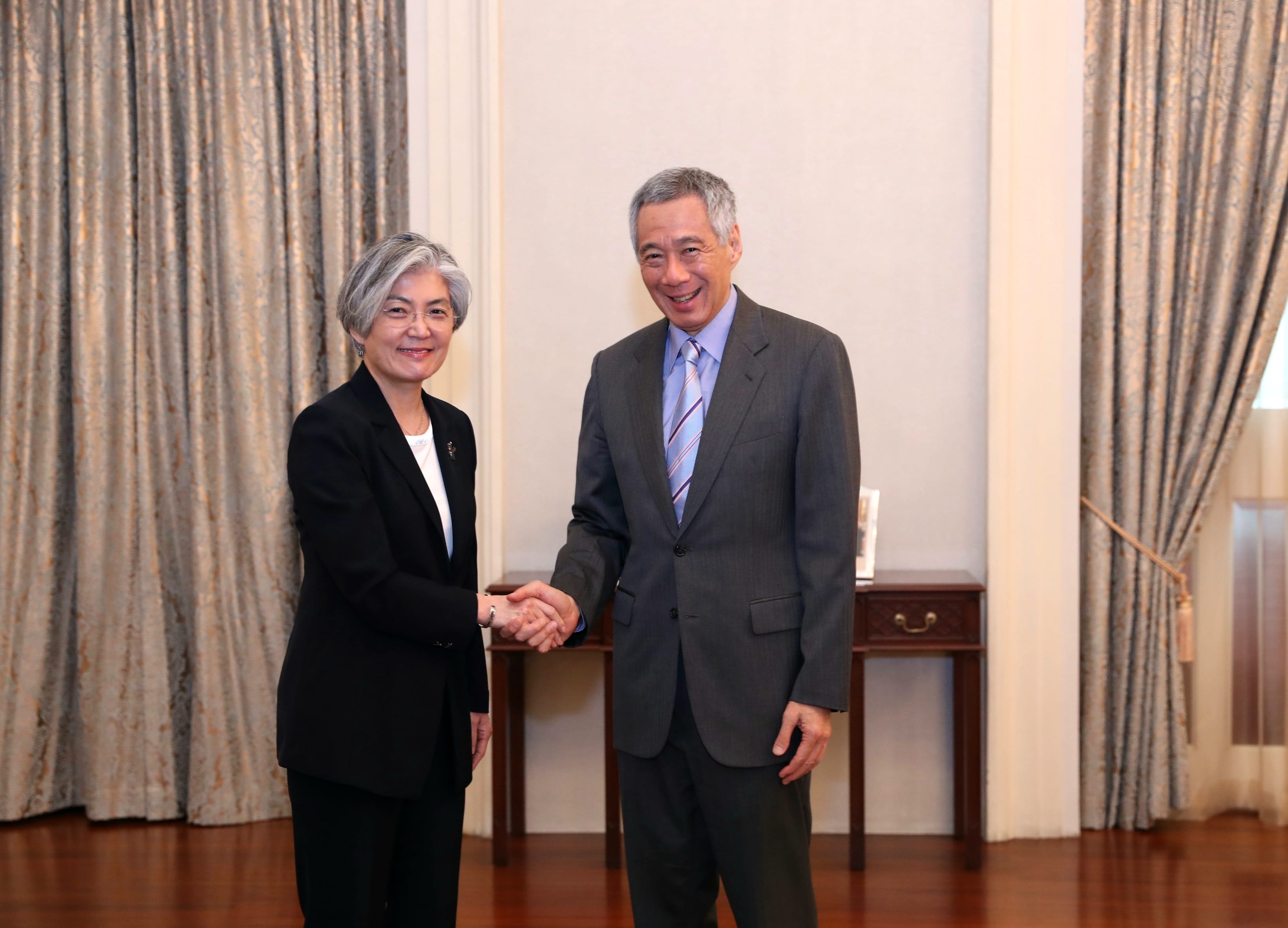 Lee Hsien Loong shaking hands with a woman in a black suit.